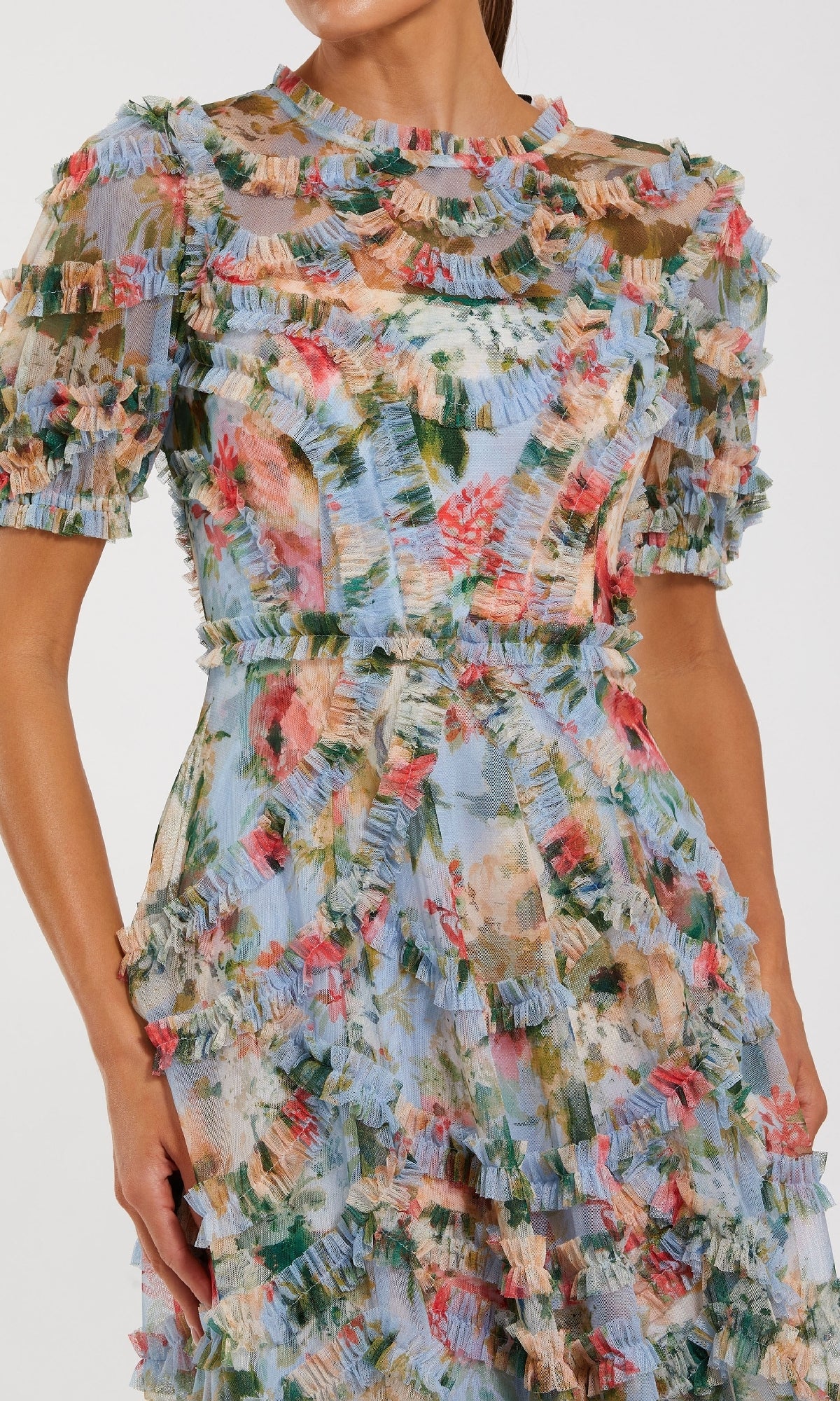 A woman wears the Mac Duggal 8302 Floral Midi Wedding-Guest Dress, featuring short sleeves, blue floral prints, ruffled details, and a fitted waist, standing against a plain background.